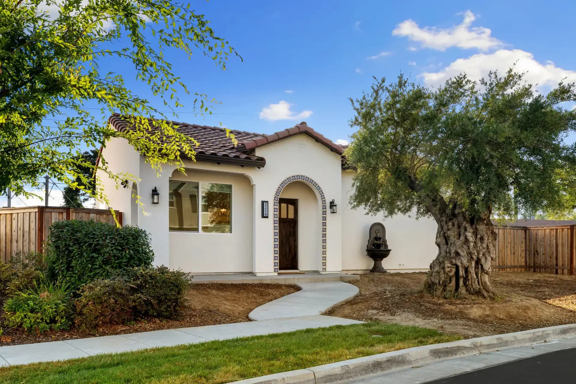 A single-storey ADU with a garden and an olive tree out front